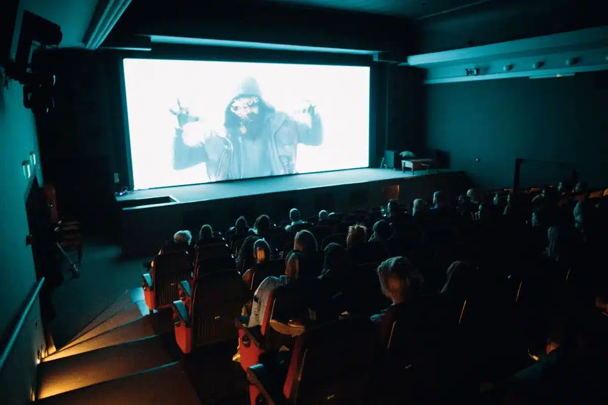 Widz siedzący przed ekranem kina w ciemności, oglądający film