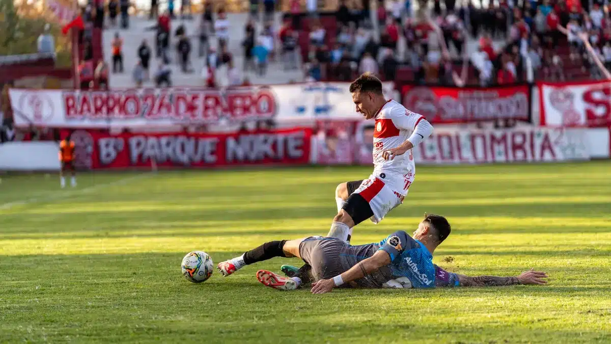Piłkarz wykonuje strzał na stadionie, obrońca próbuje zablokować akcję