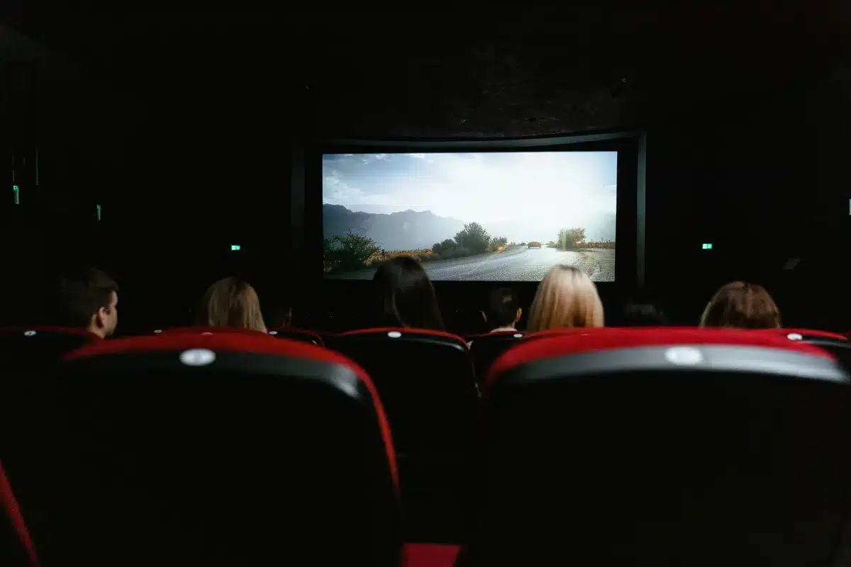 Osoba trzymająca pilot do telewizora, na ekranie widoczne sceny z polskich filmów i seriali