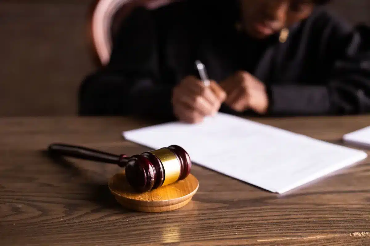 Gavel, dokumenty sądowe i smartfon wyświetlający post w mediach społecznościowych na biurku w sali sądowej
