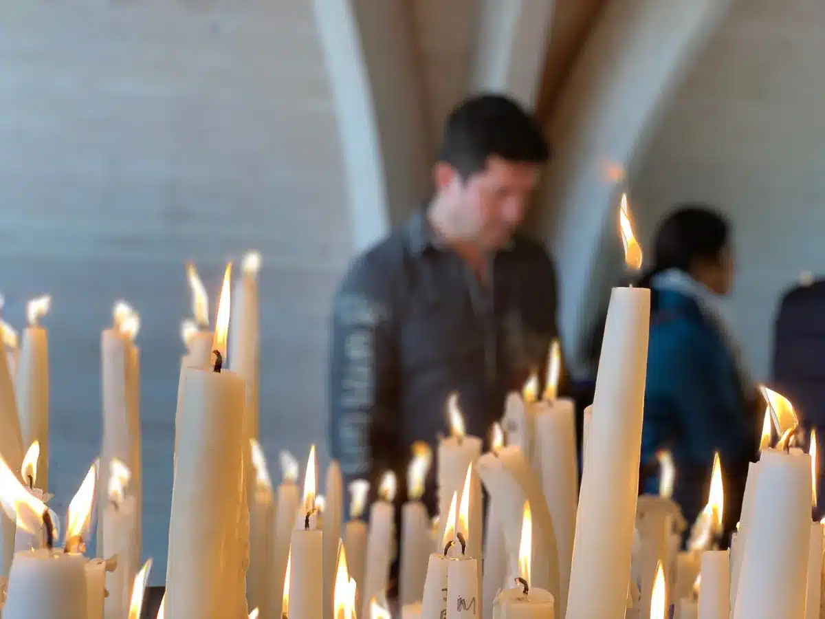 Pielgrzymi z lampionami modlący się przed sanktuarium w Lourdes