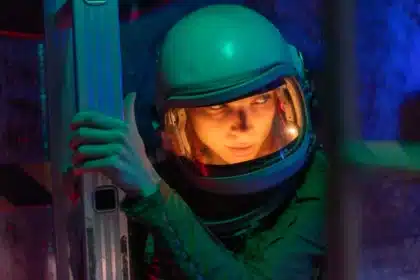 Astronauta w skafandrze obserwuje rozciągającą się przestrzeń kosmiczną z widokiem na planety i tunel czasoprzestrzenny