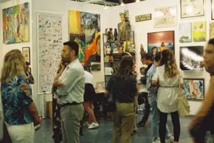 Ręce trzymające katalogi wystawowe i materiały kulturalne w nowoczesnej galerii sztuki
