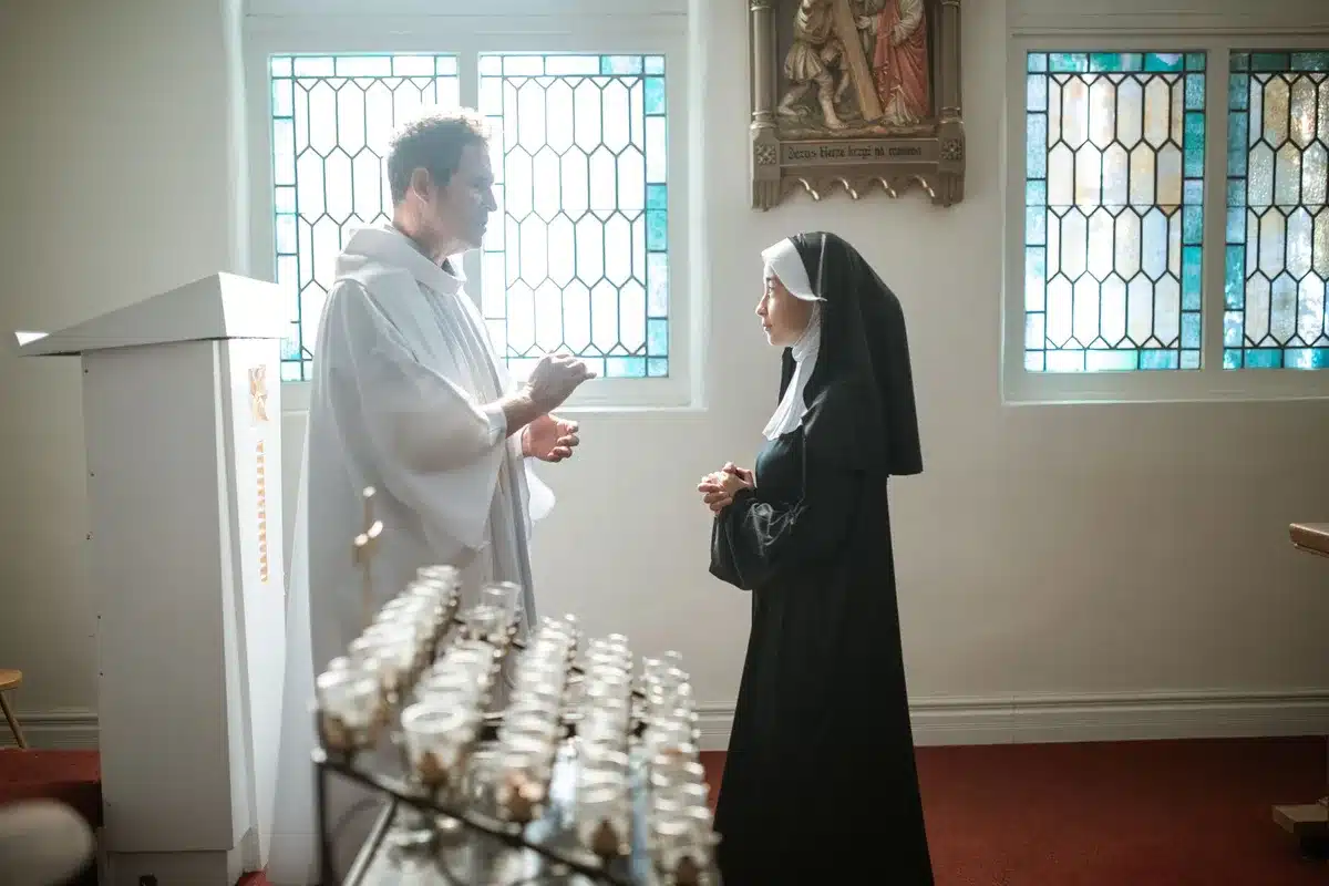 Zakonnica klęcząca w modlitwie w kaplicy oświetlonej świecami