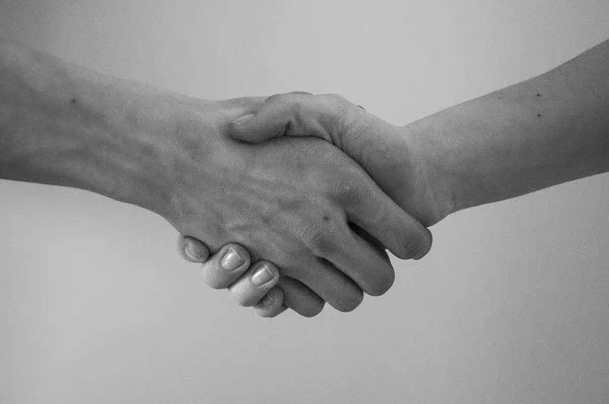 Ręce ściskające się nad dokumentami podczas oficjalnego spotkania