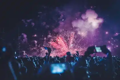 Tłum festiwalowy z uniesionymi rękami i oświetloną sceną w tle