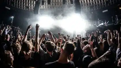Sylwetki muzyków na scenie i anonimowy tłum pod sceną