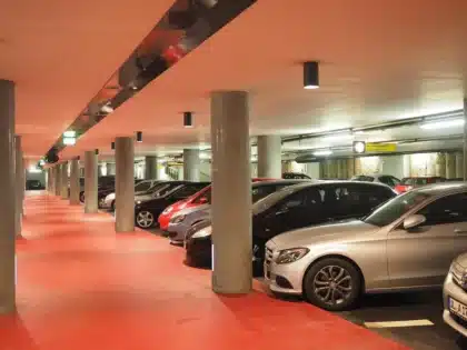 Sylwetki dwóch osób przy samochodzie na parkingu, torby na ziemi