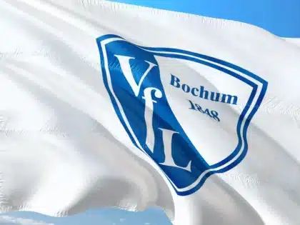 Anonimowi kibice ze szalikami na stadionie wieczorem, światła boiska w tle