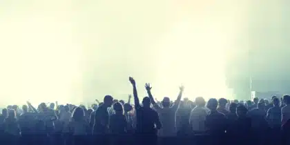 Sylwetki publiczności przed oświetloną sceną festiwalową o zmierzchu
