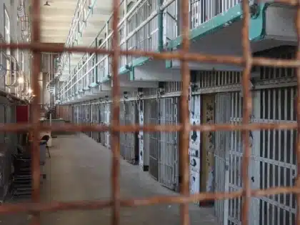 Anonimowy korytarz więzienny z sylwetkami i rozrzuconymi listami na stoliku