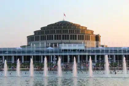 Dystansowy widok Hali Stulecia z anonimową grupą osób trzymających różańce na placu
